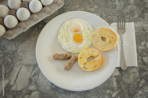 Egg sausage and bagel toast with ground black pepper on a breakfast plate.