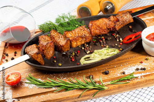 Grilled pork skewers with spices and vegetables on a pan