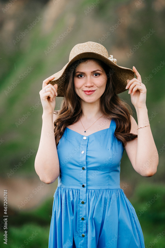 young girl in a straw hat with large brim on mountain slopes