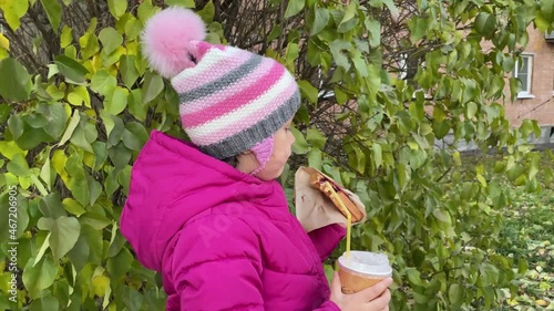 5 years old Girl eating waffles and drinking juice outside. Autumn pink clothes. Eating outdoors.