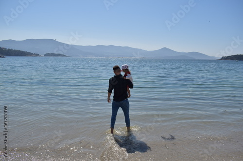 Hombre joven con una niña en brazos en la playa photo