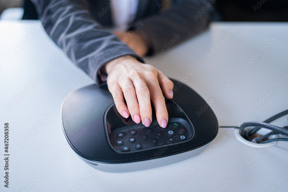 Hand on the speaker button. Business woman calling on the conference phone Hand on the speaker button. Business woman calling on the conference phone