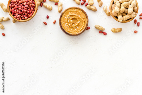 Bowls of homemade peanut butter and nuts on table, top view