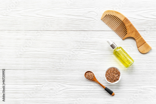 Hair treatment oil with seeds and wooden hair comb. Top view