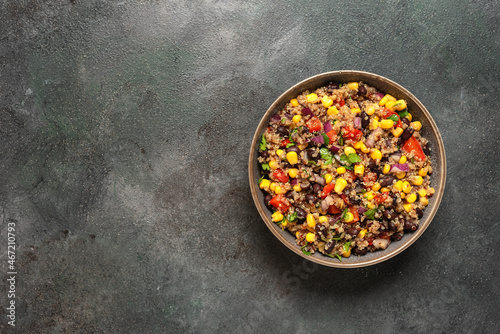 Mexican salad with black beans, corn and quinoa in a bowl on a dark grunge background. Top view.