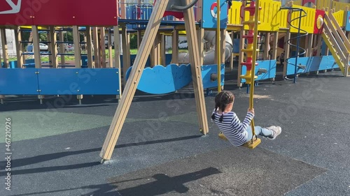 Kid riding a swing on colorful playground. 5 years old girl has fun at summer.