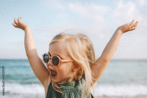 Child playing outdoor emotional surprised emotional funny girl in sunglasses 3 years old toddler raised hands family vacations outdoor photo