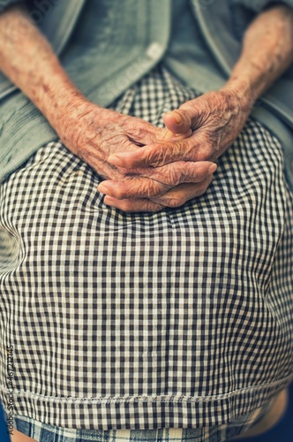 Cropped image of an older woman in plaid skirt with wrinkled hands photo