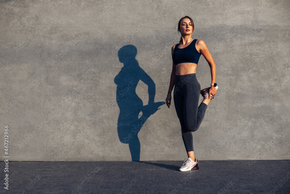 woman doing warm-up before jogging, stretching leg muscles, Female athlete prepares legs for cardio workout