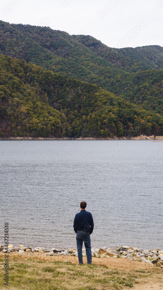 man looking out over a lake and hills