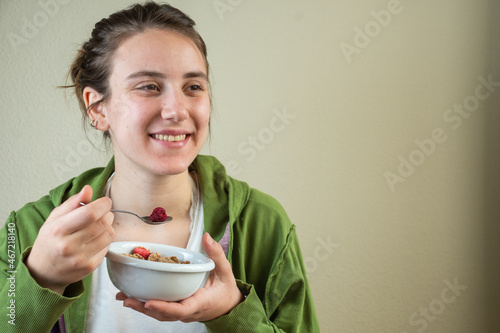 Teenage girl in green jacket eating cereal