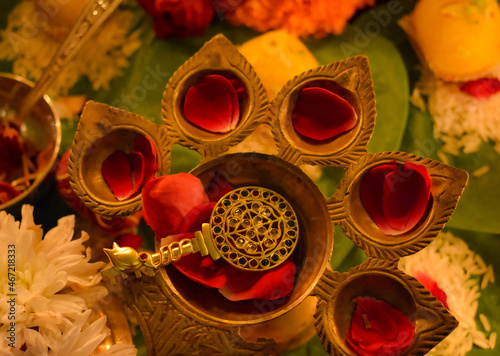 Top view of golden key with mandala head and rose petals on diya photo