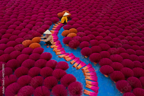 Vietnamese workers sit surrounded by thousands of incense sticks photo