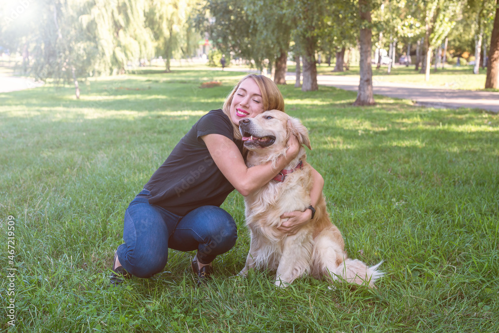 Fototapeta premium woman hugs her retriever in the park outdoors.