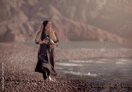 Woman in dark dress and scarf standing on seashore photo