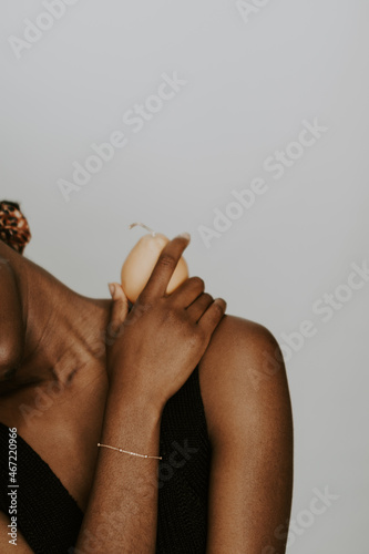 Woman wearing dark tank top and gold bracelet holding a pear photo