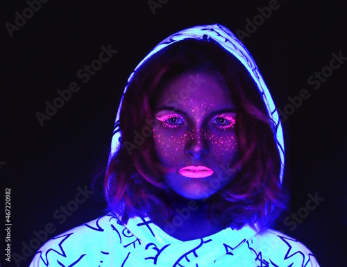 Woman wearing make-up and hoodie in an ultraviolet lit room photo