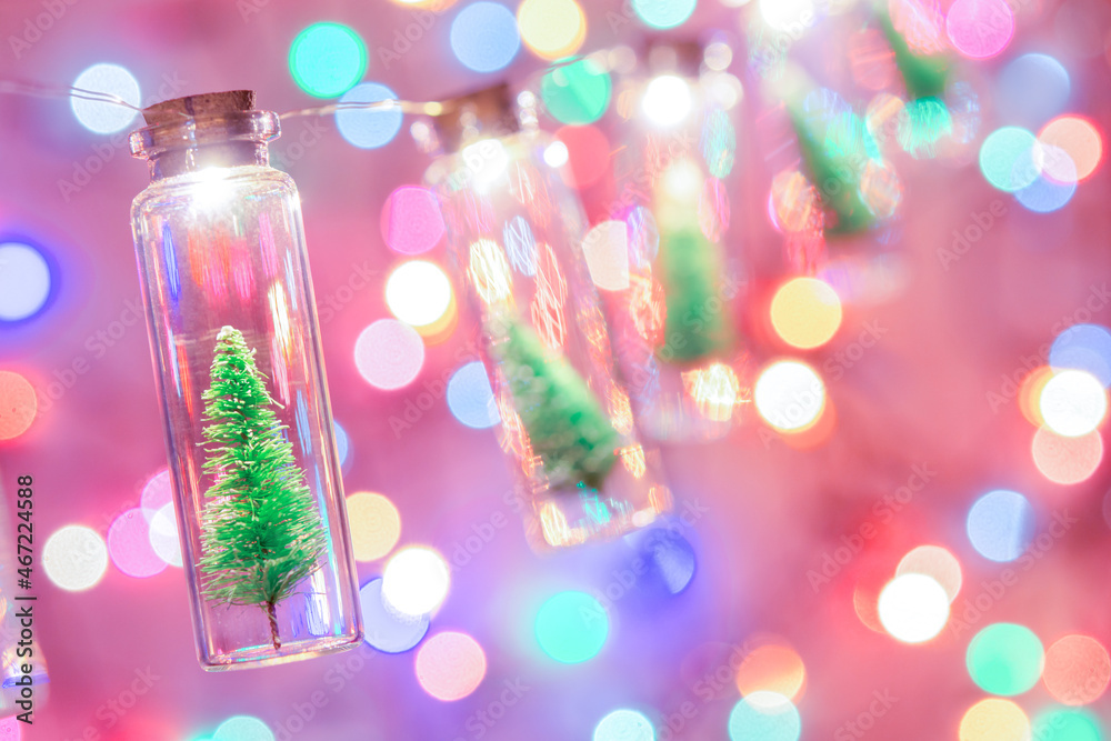 Merry Christmas and happy new year. Hanging small Christmas tree in glass jar on pine branches Christmas tree garland and ornaments over abstract bokeh Merry Christmas and happy new year. Hanging small Christmas tree in glass jar on pine branches Christmas tree garland and ornaments over abstract bokeh