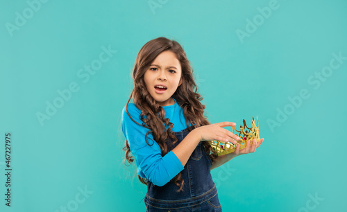 confused kid with curly hair in princess crown on blue background, selfishness photo
