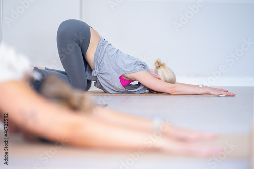 Blonde woman stretching the back on the floor during a yoga class