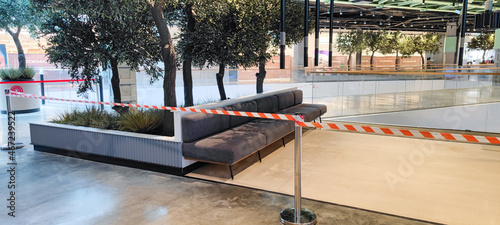 Closed, empty without people, visitors and guests and fenced off with a red ribbon is a recreation and dining area in food courts, cafes and restaurants of the shopping and entertainment center due to photo