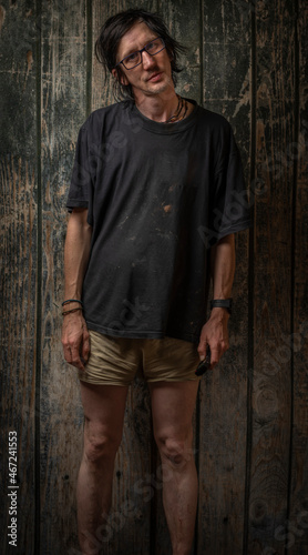 Black hair man with army shorts near wooden old wall