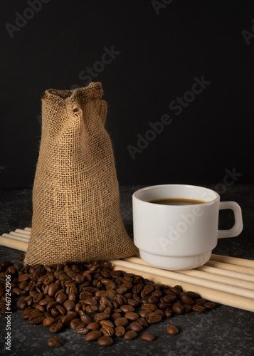cup of coffee and sack with coffee beans on black background