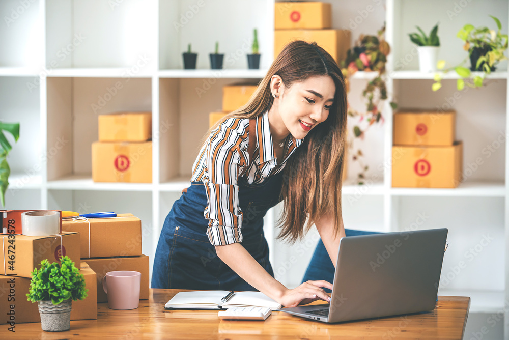 Small start-up business owners using computers at work, freelancers, saleswoman, checking production orders. Pack products for delivery to customers Small start-up business owners using computers at work, freelancers, saleswoman, checking production orders. Pack products for delivery to customers