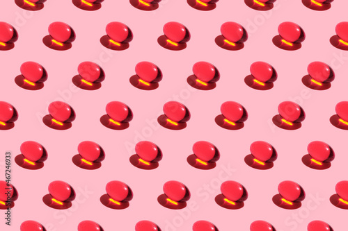 pattern of red pills. Trending image on a pink background. Medication harm concept