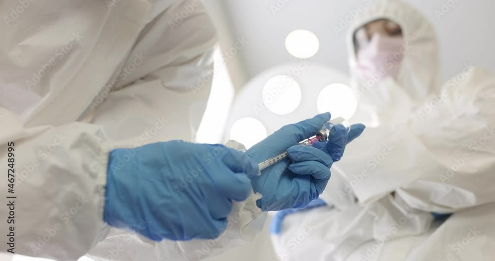 Doctor in protective suit drawing medicine from glass bottle into syringe closeup 4k movie slow motion Doctor in protective suit drawing medicine from glass bottle into syringe closeup 4k movie slow motion