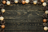 Dark wooden background with a Christmas garland and cones. Soft selective focus. Gold and brown colors.