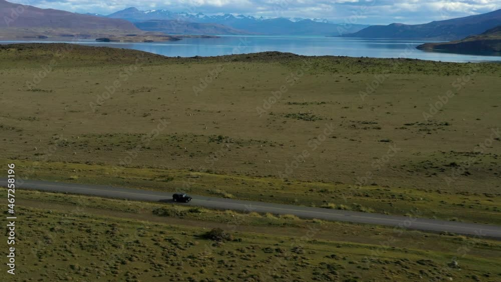 Aerial: Beautiful View Of Vehicle Moving On Road Amidst Landscape, Drone Flying Over Green Plants - Puerto Natales, Chile Aerial: Beautiful View Of Vehicle Moving On Road Amidst Landscape, Drone Flying Over Green Plants - Puerto Natales, Chile