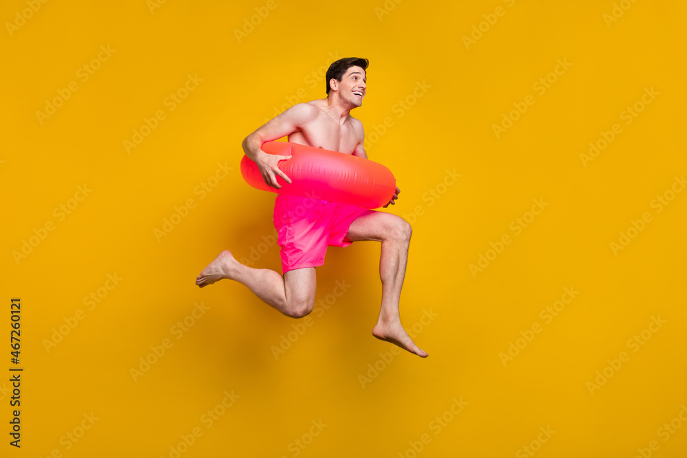 Full length profile photo of cool young guy jump wear buoy pink shorts isolated on yellow background