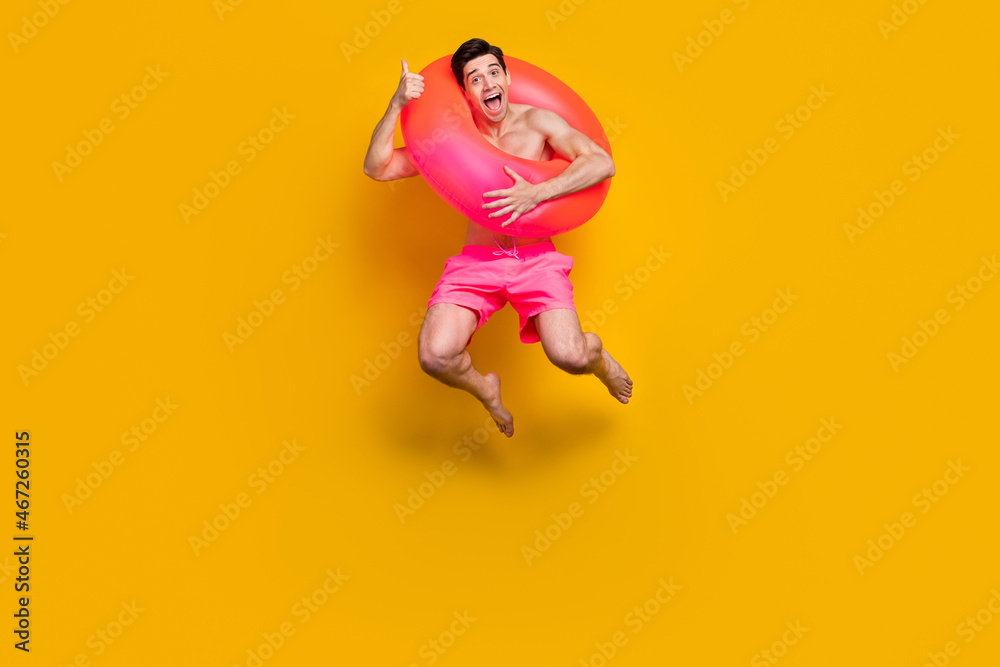 Full body photo of young excited man happy positive smile trip resort bathing circle isolated over yellow color background