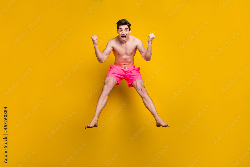 Full length photo of hooray young guy jump wear pink shorts isolated on yellow background
