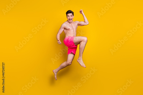 Full body profile side photo of young man happy positive smile rejoice victory jump up isolated over yellow color background