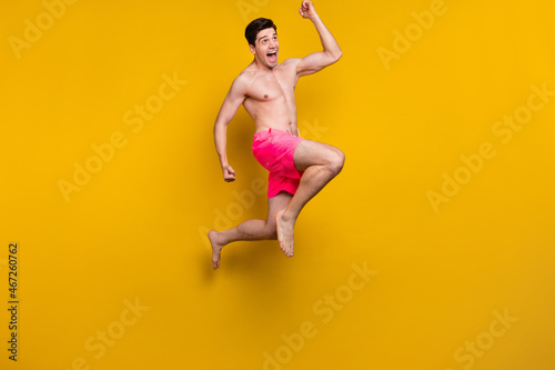 Full body photo of hooray millennial guy jump wear pink shorts isolated on yellow background