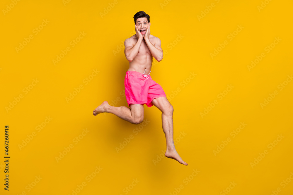 Full size photo of impressed young guy jump wear pink shorts isolated on yellow background