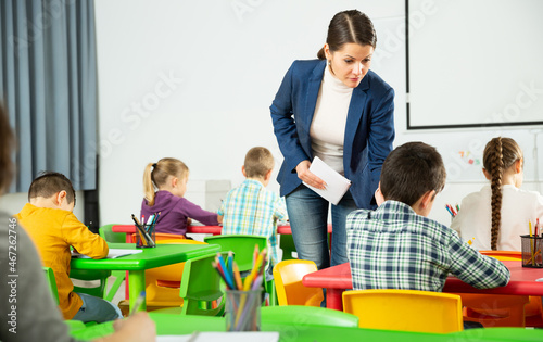 Young female teacher working with pupils in classroom at elementary school