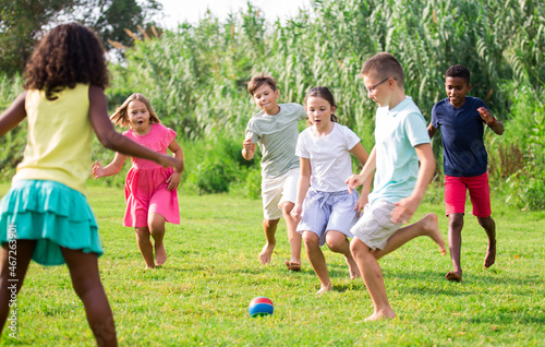 Positive kids running on field and playing football together. © JackF