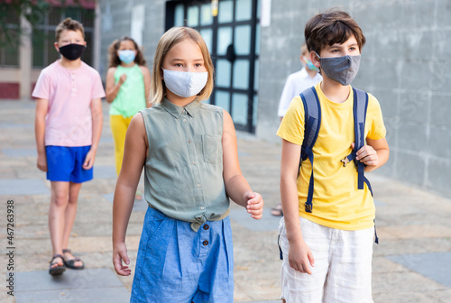 Portrait of little girl and boy wearing face mask walks along city street
