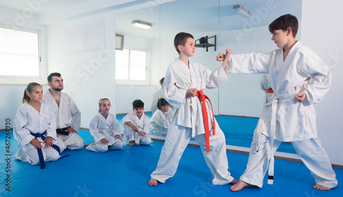 Friendly smiling boys training in pair to use karate technique during class