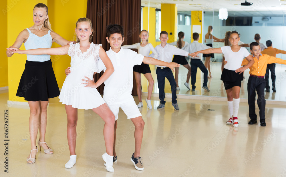 Children having dancing class with young female trainer in studio