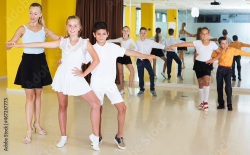 Children having dancing class with young female trainer in studio