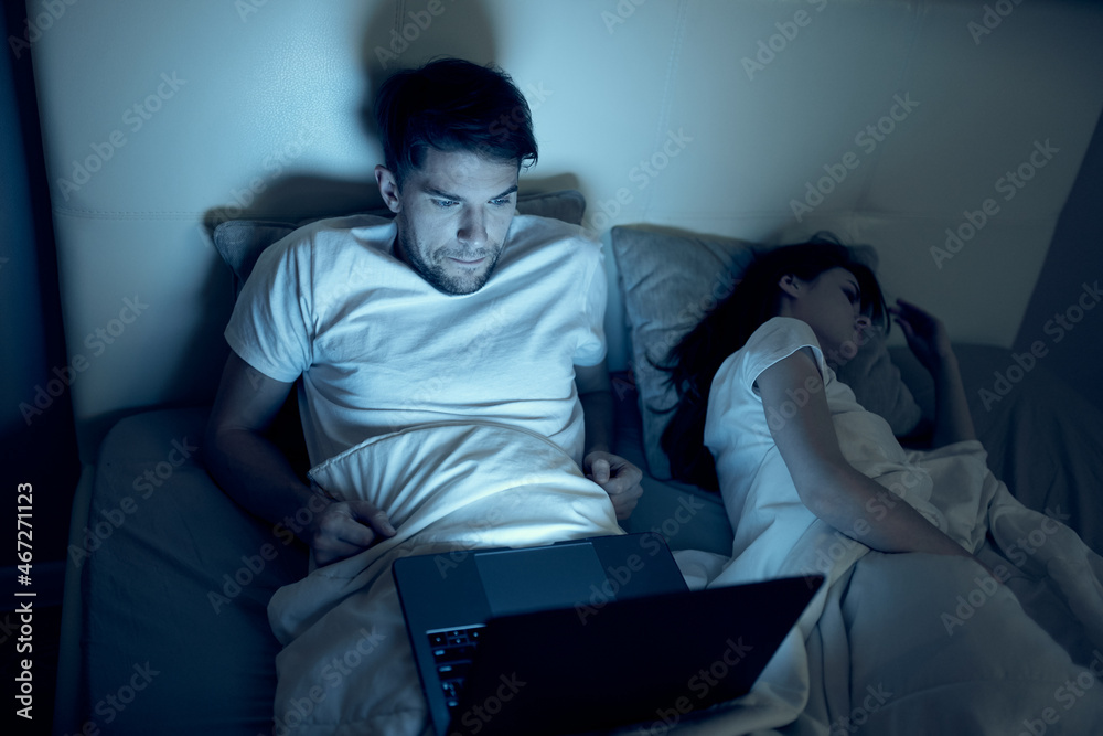 man at night in bed in front of laptop watching movies