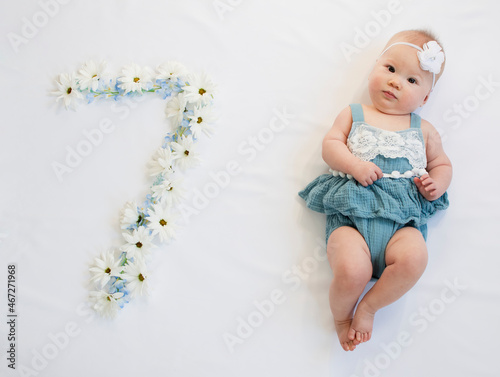 Little caucasian newborn baby girl in a blue dress. 7-month-old baby