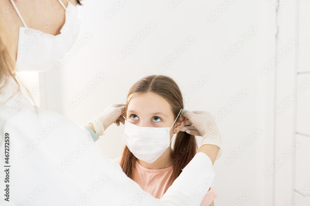 the hands of a nurse or doctor in protective gloves put a medical mask on the child girl. Viral diseases and air pollution concept. European child girl in a medical mask. children wearing mask
