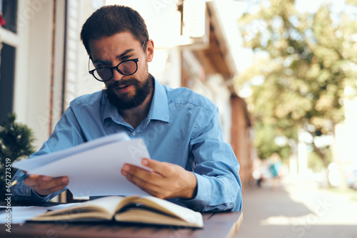bearded man in blue shirt works with papers in a cafe