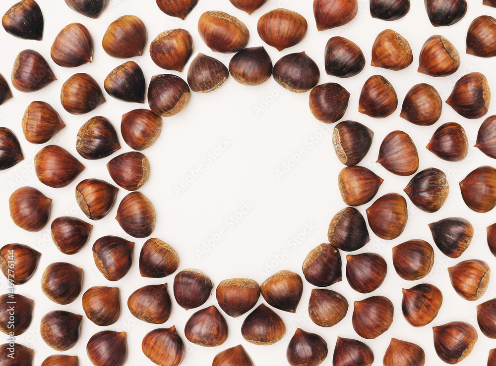 Attractive brown chestnuts arrangement with central minimal circular creative copy space. Beige background. Attractive brown chestnuts arrangement with central minimal circular creative copy space. Beige background.