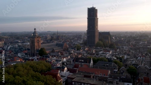 De Dom medieval cathedral tower in scaffolding and museum Speelklok at sunrise in city centre of Utrecht towering over the cityscape turning towards central station Hoog Catharijne. 60fps normal speed photo